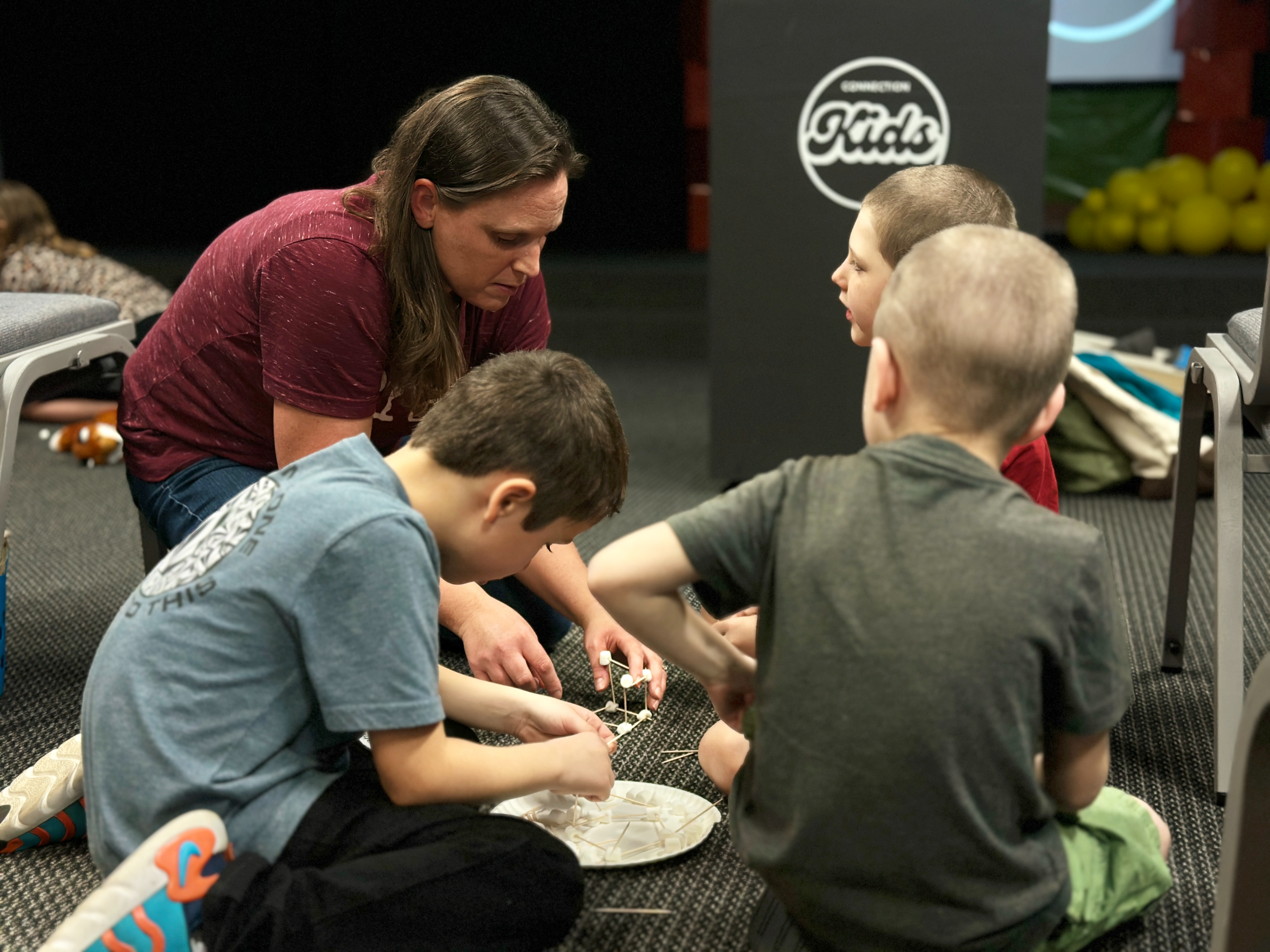 Children and a volunteer in the Connection Kids room